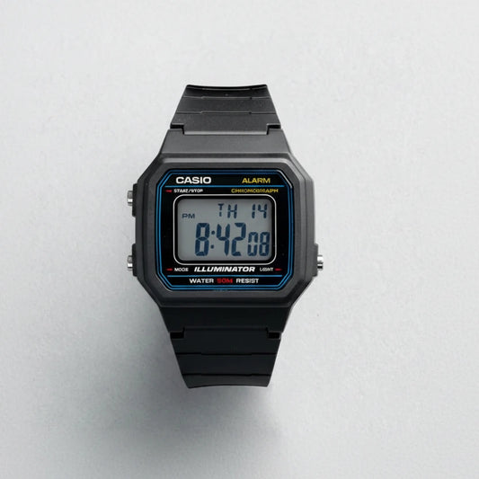 A Casio W-217H-1A digital watch with a black resin case and strap, featuring a blue and yellow bezel accent and a digital display showing 8:42:08. The Casio brand name is displayed in the top left corner, and the model number W-217H-1A is shown in the bottom right corner, all on a light gray textured background.