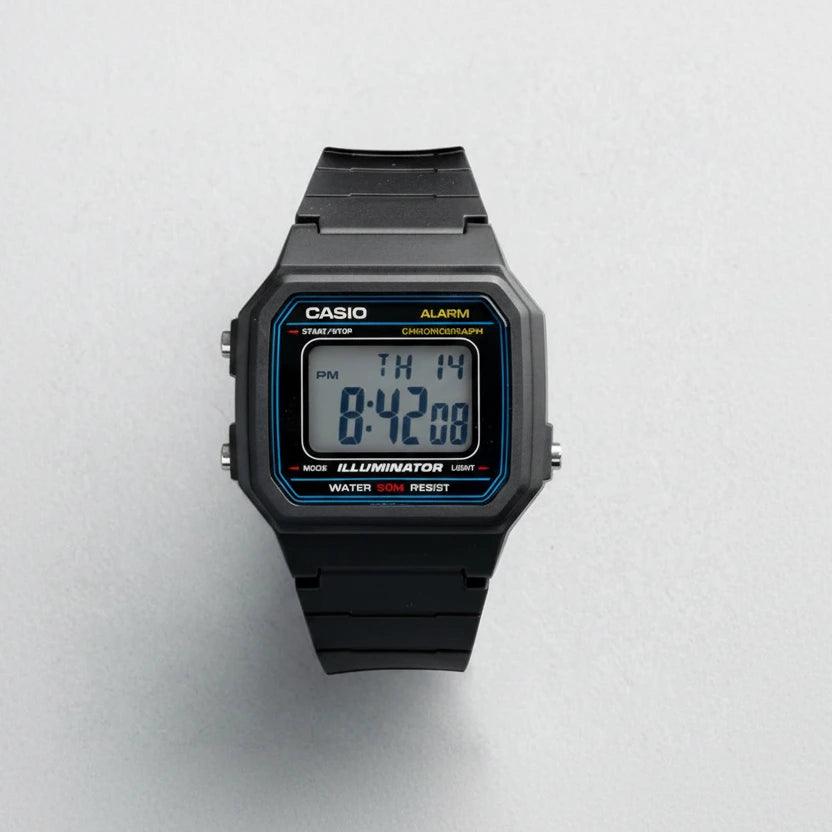 A Casio W-217H-1A digital watch with a black resin case and strap, featuring a blue and yellow bezel accent and a digital display showing 8:42:08. The Casio brand name is displayed in the top left corner, and the model number W-217H-1A is shown in the bottom right corner, all on a light gray textured background.