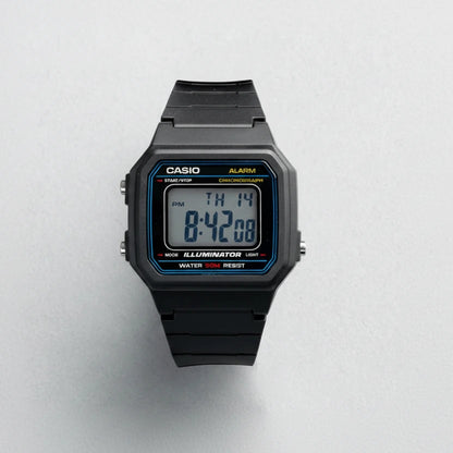 A Casio W-217H-1A digital watch with a black resin case and strap, featuring a blue and yellow bezel accent and a digital display showing 8:42:08. The Casio brand name is displayed in the top left corner, and the model number W-217H-1A is shown in the bottom right corner, all on a light gray textured background.